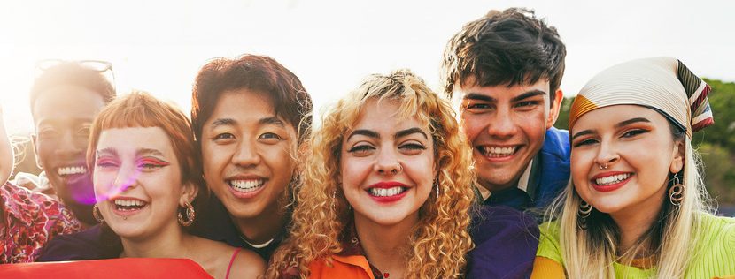 A group of LGBT youth holding a rainbow flag in front of themselves